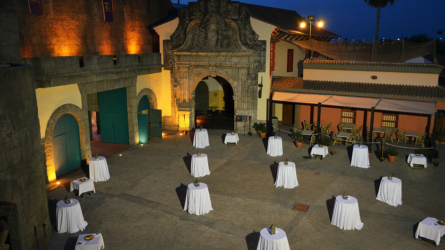 Patio al aire libre con mesas redondas de cóctel preparadas para un evento nocturno.